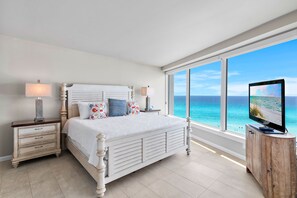 Ein Schlafzimmer mit Bett, Nachttischen, einem Fernseher und Meerblick.