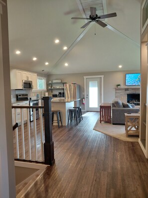A spacious kitchen with modern appliances, a dining area with a sofa and table, and a fireplace. - Start your Summer with a Vaca at the Beach Garden Bungalow (Poynette)