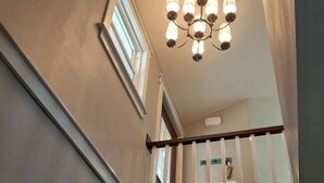 A staircase with a handrail, a chandelier, and a door with a nameplate. - Beach Garden Bungalow - Relax Near The River (Poynette)