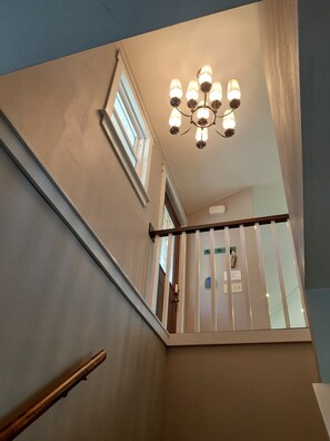 Eine Treppe mit Geländer, einer Chandelier und einer Tür mit Namensschild.