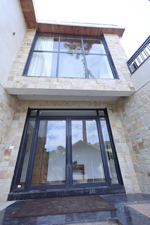 A modern building with stone facade, large glass doors, and a wooden overhang.