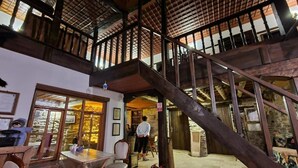 Un intérieur à plusieurs niveaux, doté d’un escalier, de poutres en bois et d’un espace d’accueil.