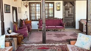 Une pièce spacieuse avec un plafond en bois, un canapé rouge, une table basse en marbre et une grande porte en bois.