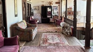 Une pièce avec un tapis à motifs, des meubles en bois et un plafond orné d’un motif en forme de quadrillage.