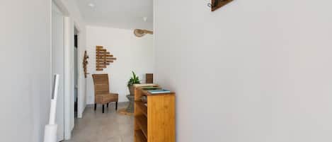 A hallway with a wooden bench, wicker chairs, and a wall-mounted sign.