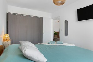 A bedroom with a bed, a grey curtain, a wall-mounted TV, and a bedside lamp. - Holiday Home 'Maison Sci Entre Foret Et Mer' with Wi-Fi (Millebosc)