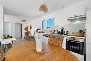 Une cuisine moderne avec une table à manger en bois, des meubles blancs et une grande fenêtre.