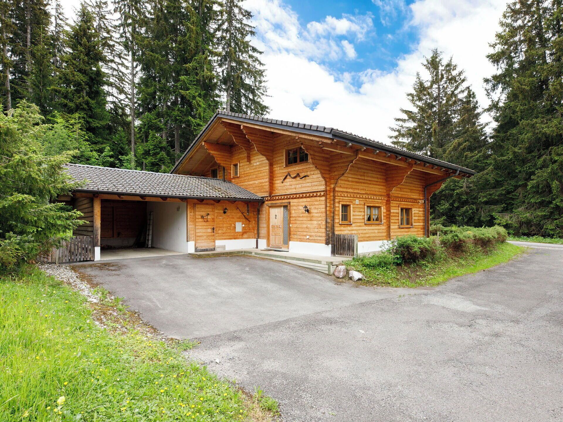 Eine Holzhütte mit überdachter Veranda und gepflasterter Auffahrt.