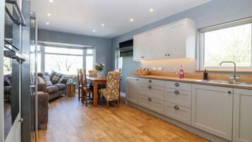 A modern kitchen with wooden cabinets, a dining area with a table and chairs, and a living room with a sofa.