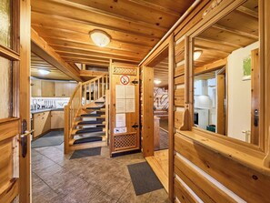 Een houten interieur met een trap naar een tweede verdieping, een keukenhoek en een deur met een rookvrij bordje.