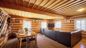 Interior de una cabaña de madera con comedor, cocina y zona de estar.