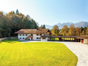 Een groot huis met een schuin dak, een overdekte veranda en een verzorgd gazon.