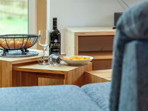 Een houten tafel met een fles wijn, een glas en een schaal met hapjes.