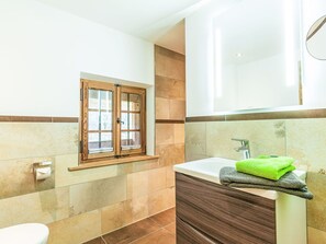 Een badkamer met een raam, een badkuip en een toilet.