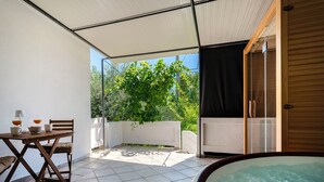 Ein kleiner Außenbereich mit Tisch, Stühlen, einem Whirlpool und einer überdachten Terrasse.