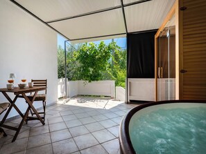 Ein kleiner Außenbereich mit Tisch, Stühlen, einem Whirlpool und einer überdachten Terrasse.
