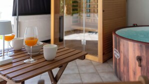 Ein Holztisch mit Gläsern und einer Tasse, eine Holzwanne und eine Glastür, die nach draußen führt.