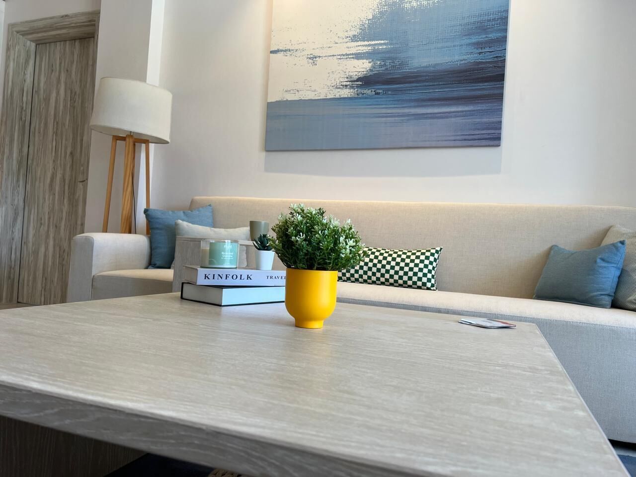 A modern living room with a sofa, a coffee table, a lamp, and a painting on the wall.