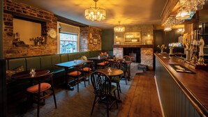 A cozy restaurant with brick walls, wooden furniture, and a bar area with a variety of bottles.