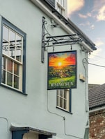 A building with a sign reading 'The Rising Sun' and a window with a view of a sunset.