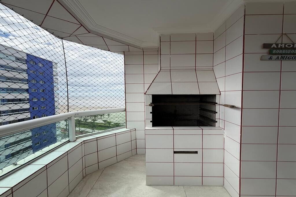 Uma varanda com vista para um edifício azul, uma parede de azulejos brancos com lareira e uma placa com a inscrição 'AMOR & AMIGO'.