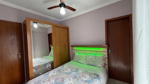 Ein Schlafzimmer mit Bett, Deckenventilator und Holztüren.