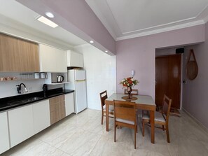 A modern kitchen with white cabinets, a black countertop, and a dining table with chairs.
