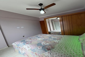 A bedroom with a bed, a ceiling fan, and a wooden wardrobe.