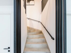 Eine Treppe mit Handlauf, Teppichstufen und einer weißen Tür am Fuß.