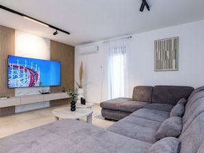 Ein modernes Wohnzimmer mit einem Flachbildfernseher, einer Couch, einem Couchtisch und einer dekorativen Vase.