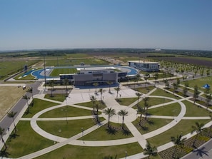 An IMG Academy Field building with a curved track, palm trees, and a clear sky.