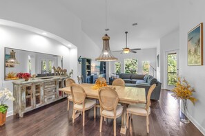 A spacious living area with a dining table, chairs, a sofa, and a ceiling fan.