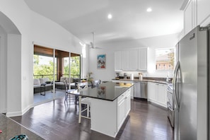 A modern kitchen with a central island, white cabinetry, and a view to an outdoor patio.