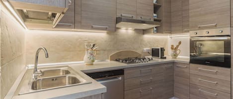 Una cocina moderna con lavavajillas integrado, pileta de acero inoxidable y cocina a gas.