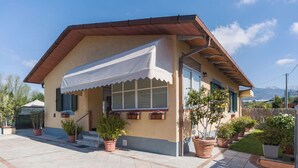 A single-story building with a sloped roof, a covered porch with a white awning, and potted plants around the entrance. - Beautiful private villa for 4 people with WIFI, A/C and TV (Massa)