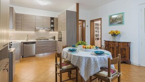 A modern kitchen with wooden cabinets, a dining table with blue plates, and a vase of sunflowers. - Beautiful private villa for 4 people with WIFI, A/C and TV (Massa)