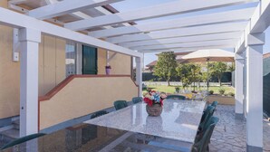 An outdoor patio with a glass-top table, green chairs, and a potted plant. - Beautiful private villa for 4 people with WIFI, A/C and TV (Massa)