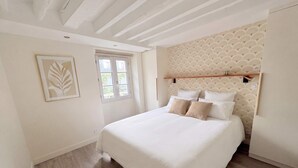 A bedroom with a bed, a window, a wall-mounted shelf, and a ceiling with exposed beams. - Heart Marais Bright 1BR by Melvane (Paris)