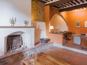 Ein rustikales Interieur mit Kamin, Steinwand, Holzbalken und einer gemütlichen Sitzecke.