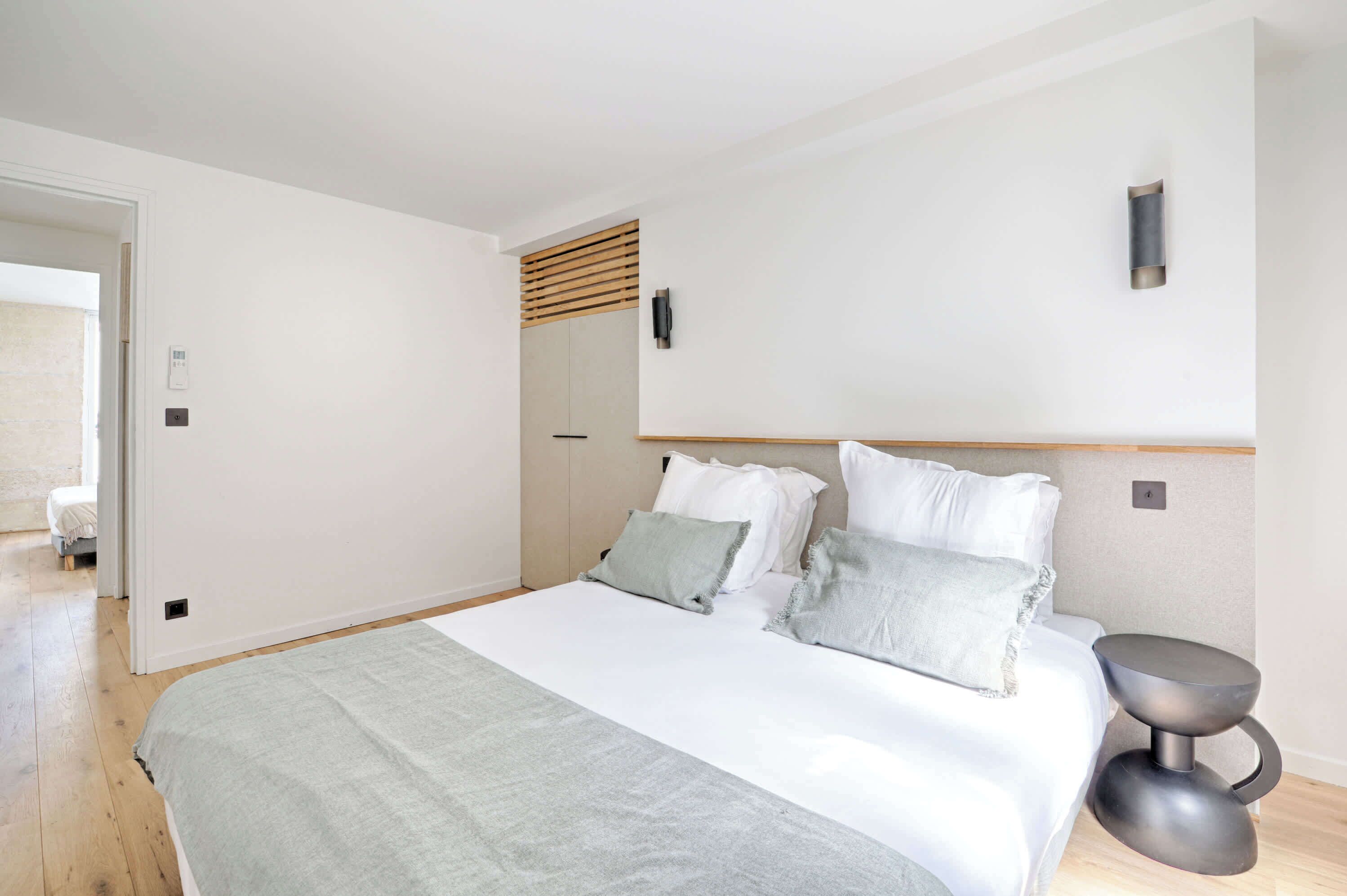 A bedroom with a bed, bedside table, and a wall-mounted light fixture.