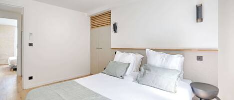 A bedroom with a bed, bedside table, and a wall-mounted light fixture.