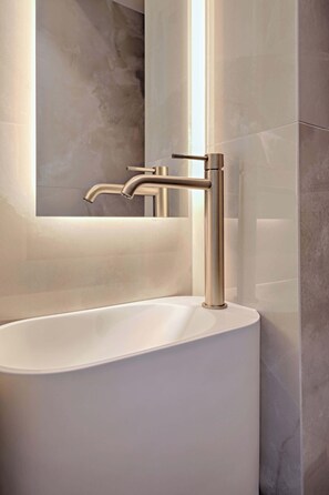 Une salle de bain moderne avec un lavabo blanc, un robinet chromé et un miroir au-dessus du lavabo.