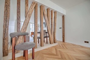 A modern interior with wooden beams, a herringbone floor, and a grey upholstered chair. - Heart Marais Bright 2B, 6P, AC by Melvane (Paris)