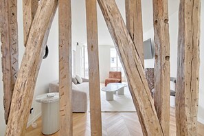 Un salon moderne avec un parquet en chevrons, un canapé, une table basse et un téléviseur fixé au mur.