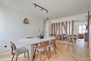 Un espace repas moderne avec une table en marbre, des chaises en bois et un parquet à motifs en chevrons.
