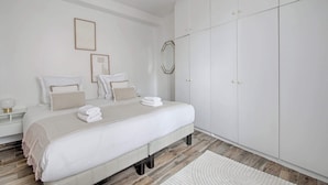 Ein Schlafzimmer mit Bett, Nachttischen, einem Kleiderschrank und einem Spiegel.