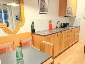 A compact kitchen with wooden cabinets, a built-in microwave, and a small sink. - Heart of Saint Germain 1B,4P,AC (Paris)