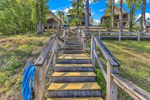 A wooden staircase leading to a building with multiple levels, surrounded by trees and a clear sky. - New! No Worries on Lake Martin 3BR/3BA that sleeps 10, pets OK! (Dadeville)