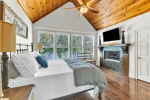 A bedroom with a bed, a ceiling fan, a fireplace, and large windows. - New! No Worries on Lake Martin 3BR/3BA that sleeps 10, pets OK! (Dadeville)