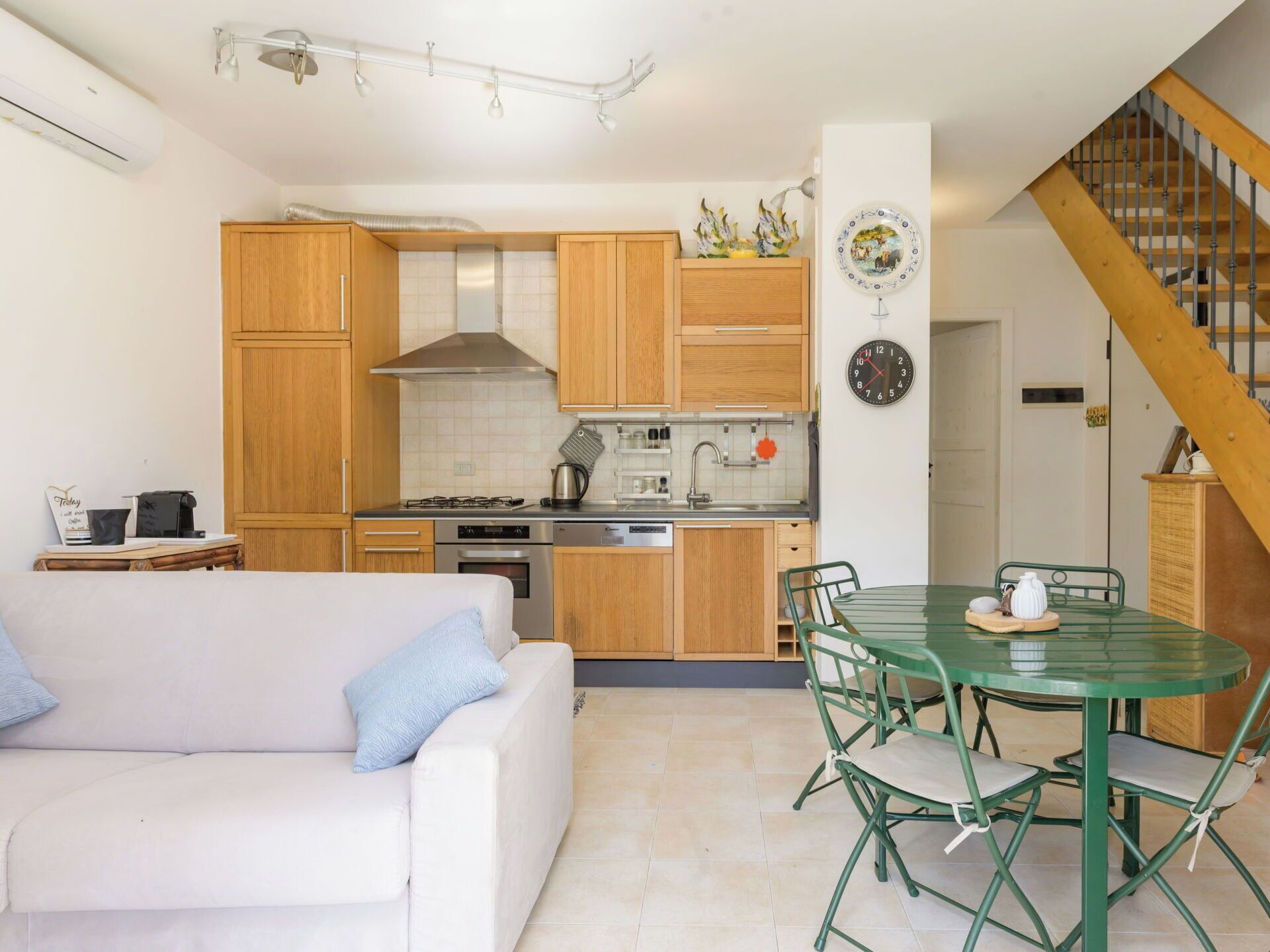 Una cocina compacta con armarios de madera, una estufa y un comedor con una mesa y sillas verdes.